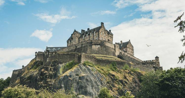Le majestueux château d'Édimbourg perché au sommet d'une roche volcanique sous un ciel bleu.
