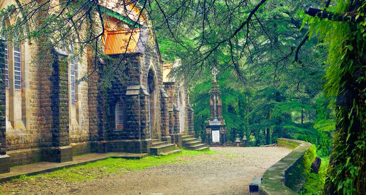 Mossy stone church and pathway framed by misty cedar trees in a lush Himalayan hillside setting.