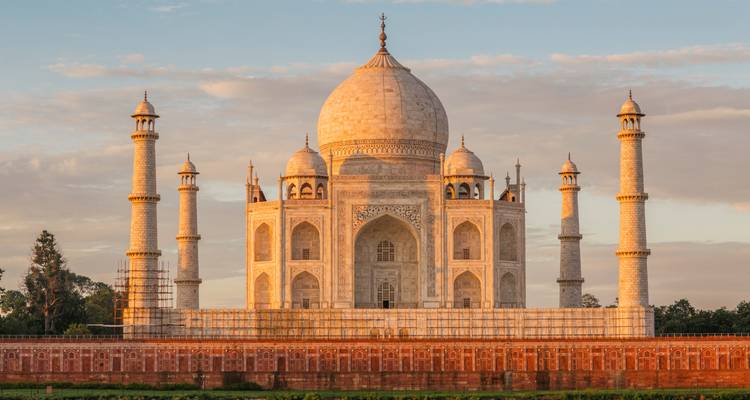 The immaculate white marble Taj Mahal stands majestically against a pastel dawn sky.
