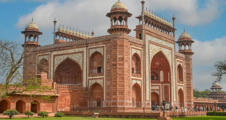 Visitors gather at the grand red-sandstone gateway leading into the Taj Mahal complex.