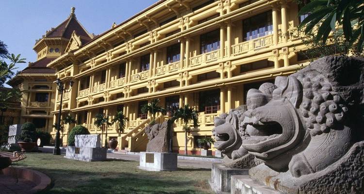 Musée national d'histoire du Vietnam de style colonial français jaune avec des statues de gardiens en pierre.