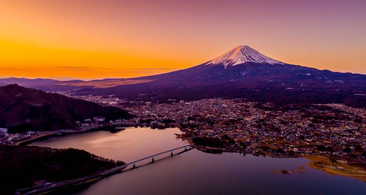 Vista aérea espectacular del Monte Fuji sobre el Lago Kawaguchi en una puesta de sol de un naranja brillante.