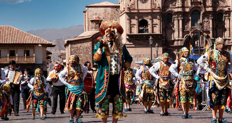 Colourful folk procession with musicians and dancers in ornate costumes parading through Cusco’s historic plaza.