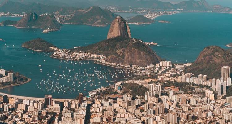 Sweeping aerial view of Rio de Janeiro’s Sugarloaf Mountain and surrounding bays under clear skies.