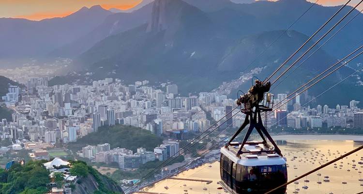 Cable car approaching Sugarloaf Mountain over Rio harbour during warm twilight.