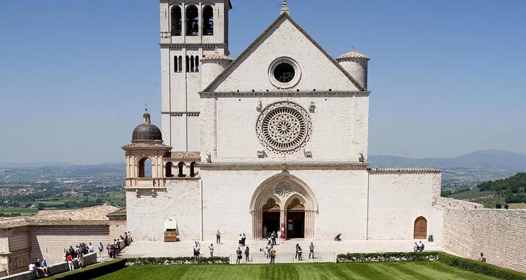 Façade avant de la Basilique Saint-François d'Assise avec des visiteurs sur la pelouse verte