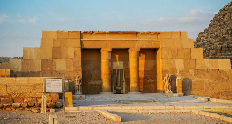 Una luz dorada del atardecer ilumina un pequeño pabellón de templo de piedra en la Meseta de Giza.