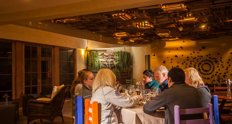 Travellers enjoy a candlelit dinner in a warmly lit restaurant with artistic wooden ceiling décor.