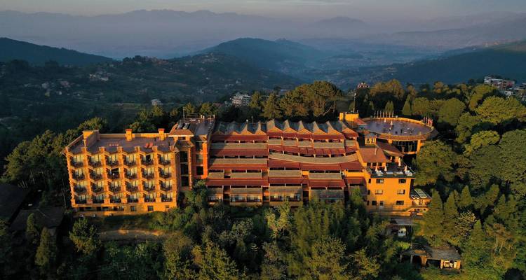 Complejo turístico en la ladera con arquitectura en terrazas ubicado entre pinos al atardecer.