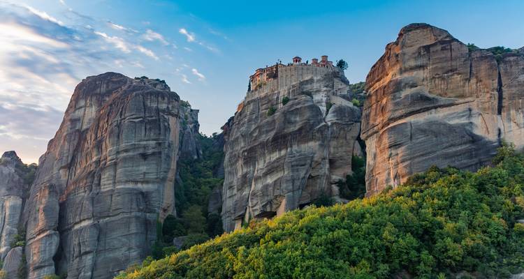 Dramatic sandstone pillars of Meteora topped with an ancient monastery against a blue sky