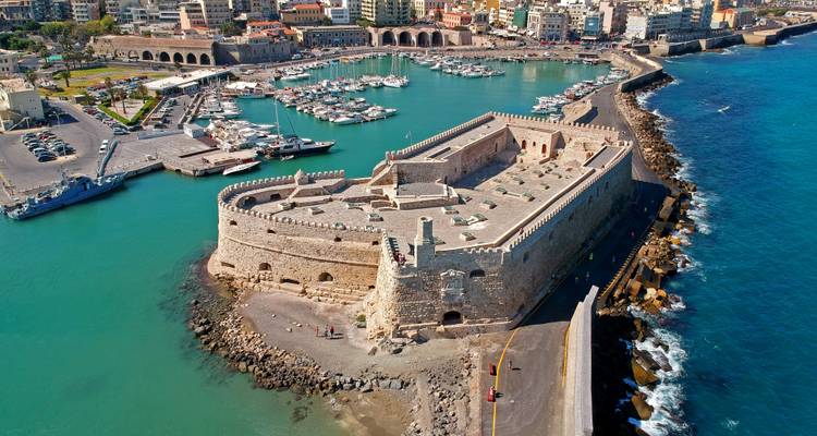 Aerial view of Venetian fortress guarding a marina filled with boats in turquoise waters