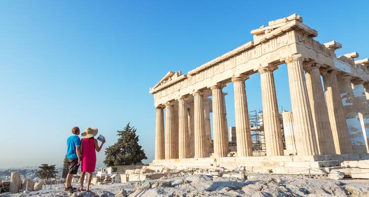 Couple in bright clothing admiring the Parthenon’s towering columns on a sunny day