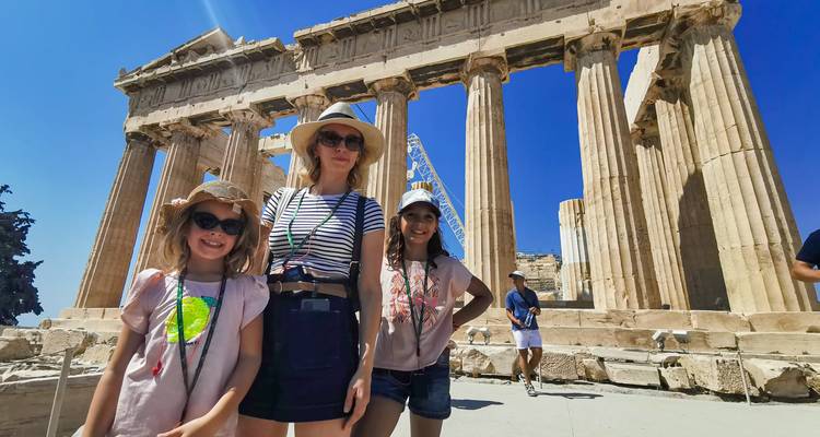 Family posing happily in front of the Parthenon with bright summer sky overhead