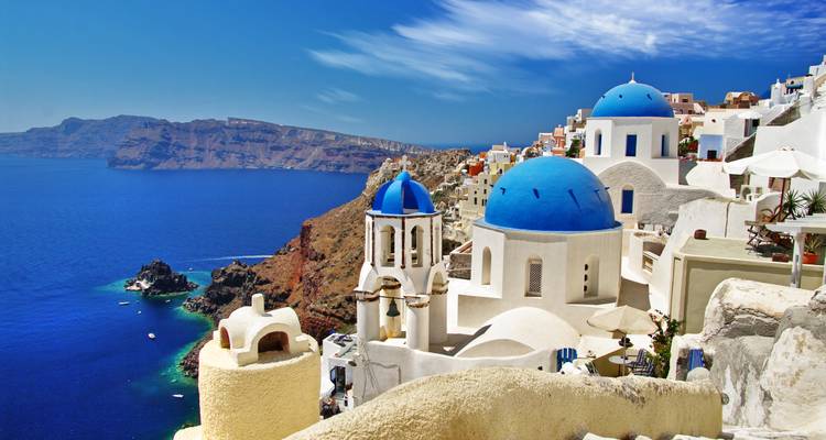 Iconic blue-domed churches overlook caldera cliffs and deep blue Aegean Sea in Santorini