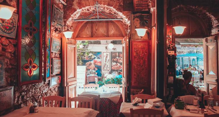 Warmly lit interior of a rustic Greek taverna with stone walls and colourful stained glass
