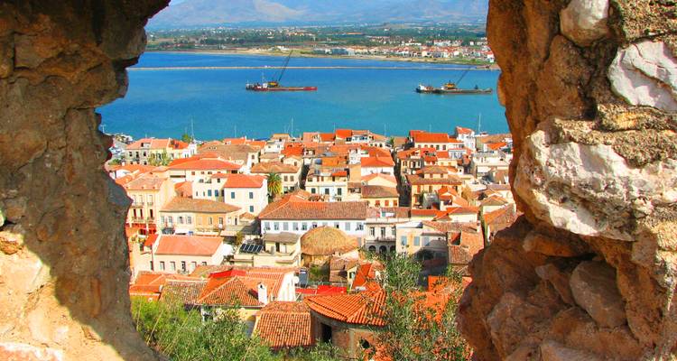 View of Nafplion's red-roofed old town and blue gulf seen through a stone fortress window