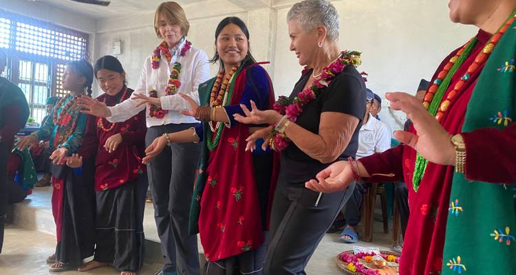 Les visiteurs se joignent aux femmes locales vêtues de robes traditionnelles rouges pour une danse folklorique intérieure animée, tous portant des guirlandes de fleurs.