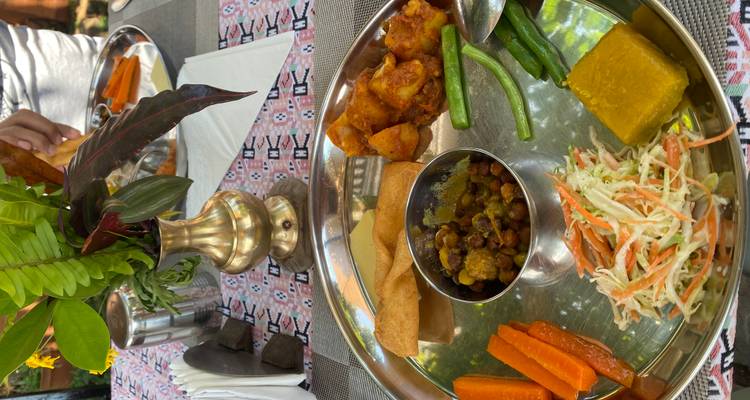 Plateau-repas népalais coloré avec légumes, légumineuses, papad et curry servi sur un thali en métal.