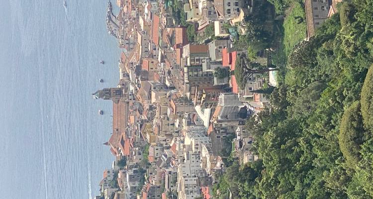 Vue surplombante sur une ville côtière aux toits en terre cuite avec un clocher central et la mer Tyrrhénienne au-delà.
