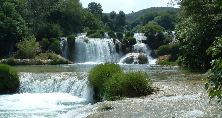 Die mehreren Wasserfälle des Krka-Nationalparks stürzen an einem Sommertag durch üppiges Grün hinab