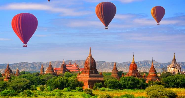 Los coloridos globos aerostáticos flotan sobre la antigua llanura llena de templos de Bagan bajo un cielo despejado.