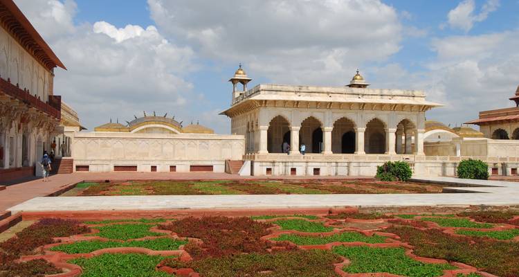 Marmeren paviljoens en verzorgde Mughal-tuinen in de binnenplaats van het Agra Fort onder wollige wolken.