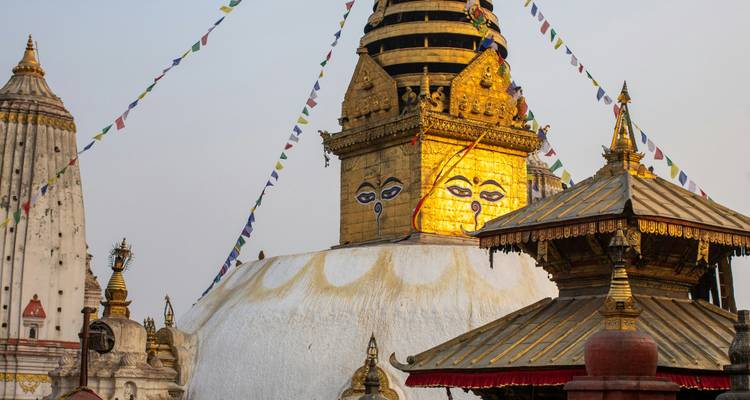 Les flèches dorées et les yeux omniscients de Swayambhunath Stupa s'élèvent au-dessus des toits de temples ornés au crépuscule.