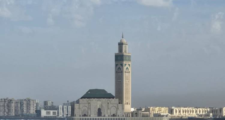 Casablanca’s Hassan II Mosque rises majestically on the Atlantic shore beneath scattered clouds.