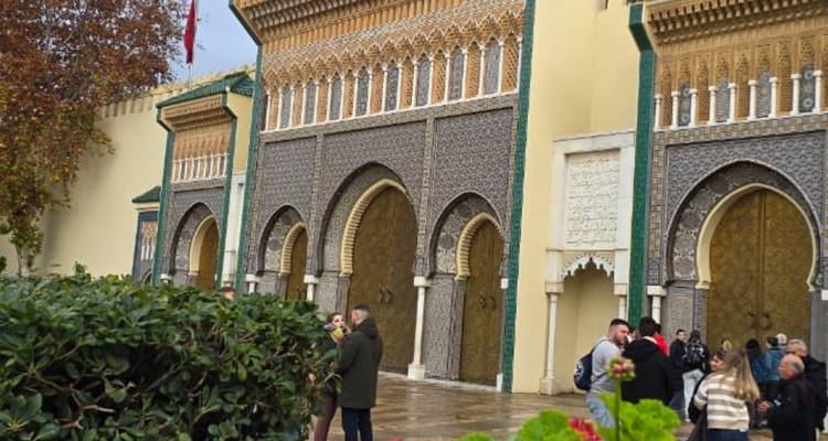 Visitors gather outside the ornate bronze doors and mosaic arches of the Royal Palace Gate in Fes.