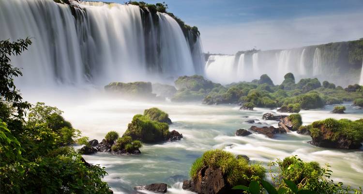 Dramatische Aussicht auf die Iguazu-Fälle mit aufsteigendem Nebel und üppig grüner Vegetation rundherum.