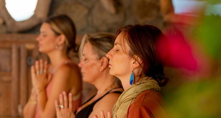 Frauen, die an einer Meditations- oder Yoga-Sitzung in einer rustikalen Steinloge teilnehmen.
