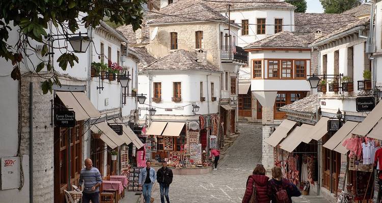 Calle del mercado tradicional en Krujë con adoquines empinados y puestos de madera vendiendo artesanías albanesas.