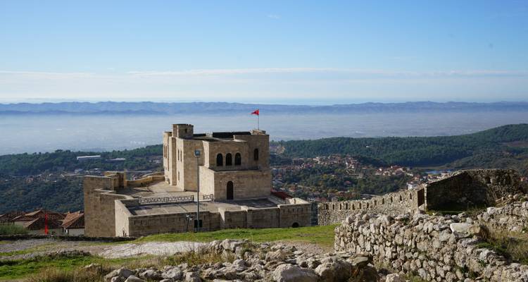 El Castillo de Piedra Krujë con la bandera albanesa domina una colina con vistas panorámicas del valle.