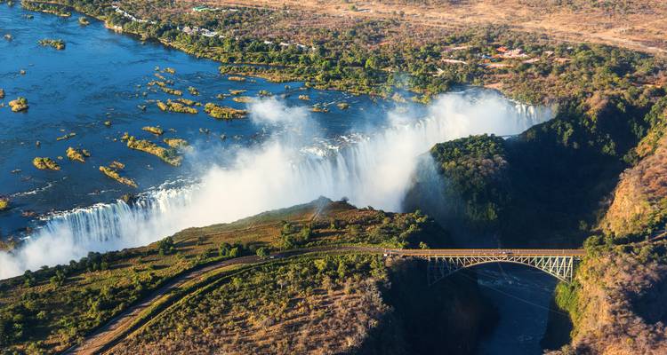 Aerial view of thunderous Victoria Falls and iconic bridge spanning deep gorge