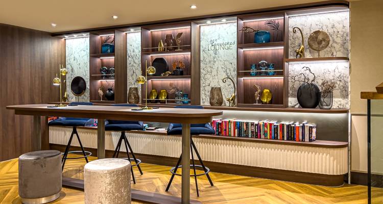 Stilvolle Lounge mit Holzakzenten, Marmorregalem und einem Bücherregal mit Romanen