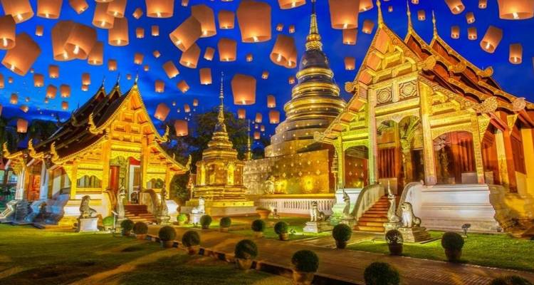 Scène nocturne d'un complexe de temple illuminé avec des centaines de lanternes flottantes s'élevant dans le ciel.