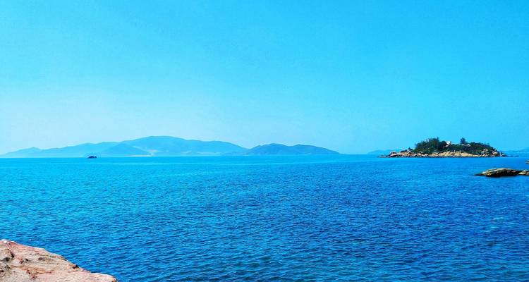 Vaste étendue de mer turquoise éclatante avec des îles basses lointaines à l'horizon sous un ciel dégagé.