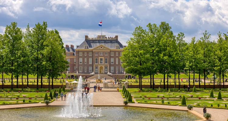 Jardines formales y fuente que conducen al Palacio Het Loo en Apeldoorn bajo un cielo parcialmente nublado.