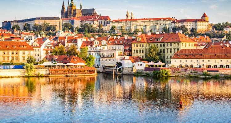 Vue lumineuse de jour du complexe du Château de Prague et des maisons aux toits rouges se reflétant dans la rivière Vltava.