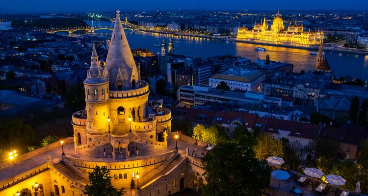 Vue nocturne de la Bastion des Pêcheurs surplombant le Parlement hongrois illuminé de l'autre côté du Danube.