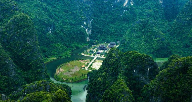 Perspective aérienne élevée des pics de calcaire luxuriants et verdoyants ainsi qu'une vallée cachée avec des temples à Ninh Binh.