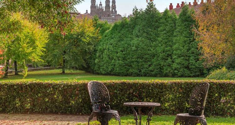 Las sillas y mesa de hierro del jardín dan vistas a los setos bien cuidados y a las dos torres lejanas de la catedral de Santiago de Compostela.