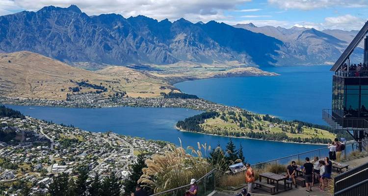 Vue panoramique sur Queenstown et le lac Wakatipu avec des visiteurs profitant du belvédère de la skyline.