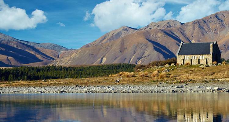 L'église en pierre du Bon Pasteur est située au bord des eaux bleues et calmes du lac Tekapo sous un ciel dégagé.