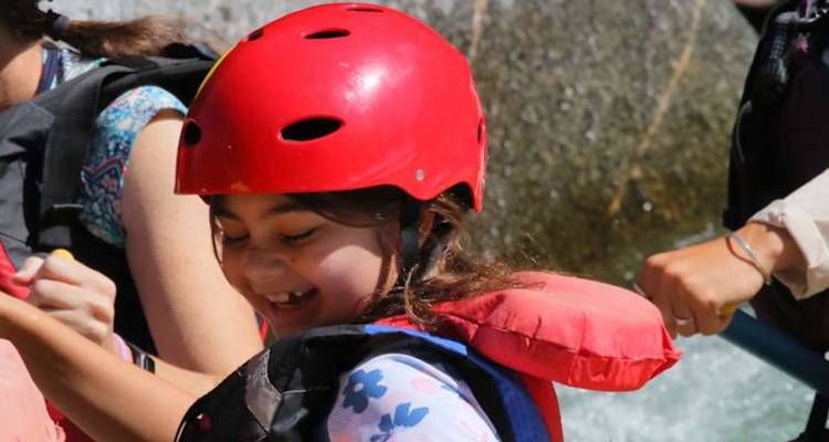 Gros plan d'un enfant souriant portant un casque rouge pendant une séance de rafting.