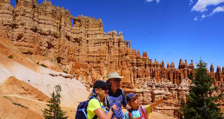 Une famille signale les impressionnants hoodoos orange qui se dressent dans le canyon de Bryce sous un ciel d'un bleu éclatant.