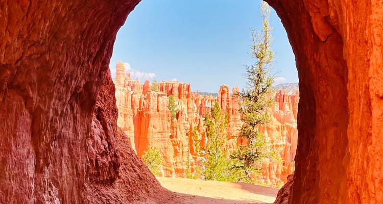 Les hoodoos orange du Bryce Canyon vus à travers une ouverture naturelle de grotte dans la roche rouge.