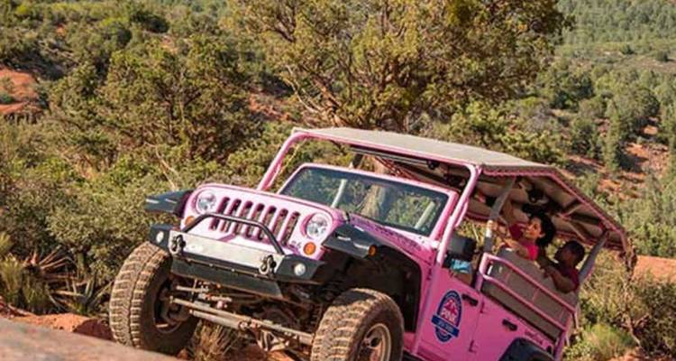 Un véhicule de safari rose grimpe un obstacle de roche rouge lors d'une excursion hors route à Sedona.