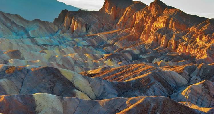 Les badlands colorés et érodés ainsi que les crêtes illuminées par le soleil au point Zabriskie dans la Vallée de la Mort