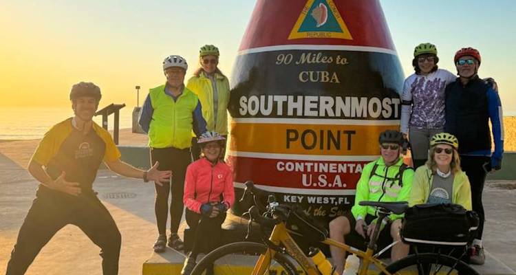 Fietsgroep poseert bij de iconische Southernmost Point boei in Key West bij zonsopgang